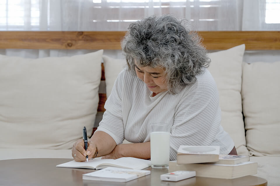 A woman writing in a notebook at home