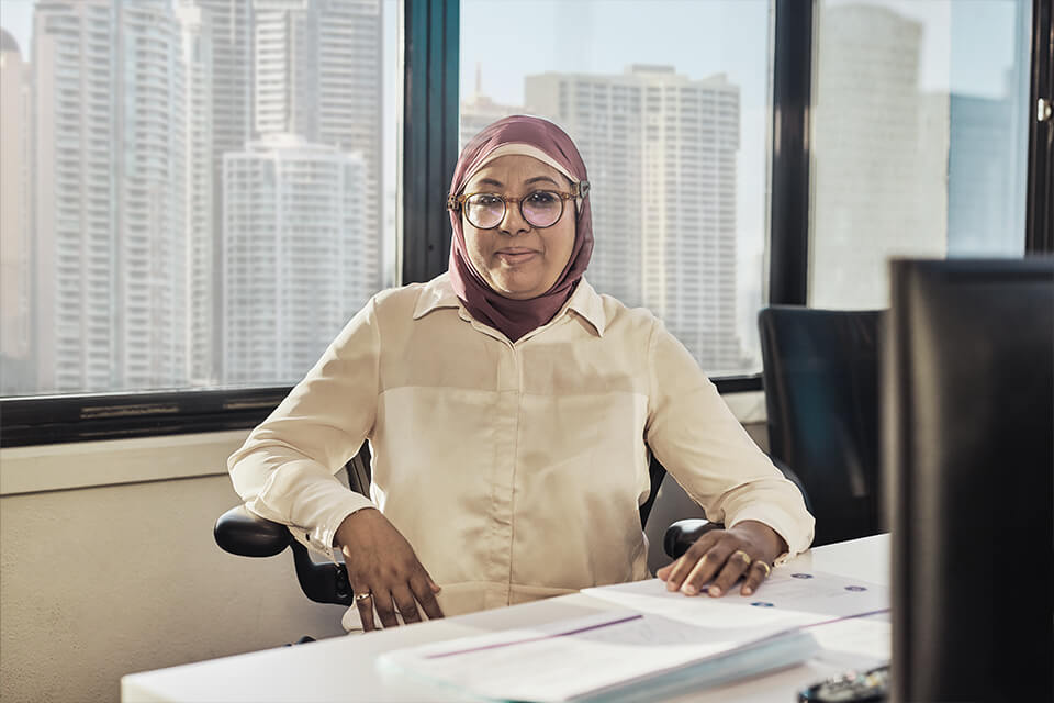 A lady sitting at a desk in an office looking at the camera